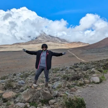 a woman standing on a rock with her arms out in the air